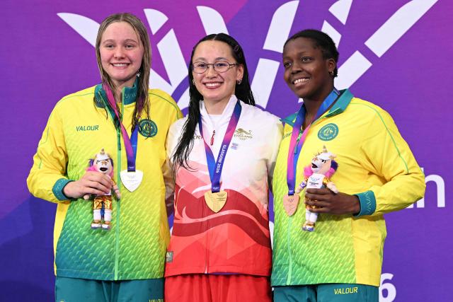 Silver medallist Australia's Gemma Sellick, gold medallist England's Alice Tai and bronze medallist Australia's Victoria Belando Nicholson celebrate during the Women's 100m Backstroke S9 medal ceremony at the swimming event at the Tollcross International Swimming Centre in Glasgow, on day three of the Commonwealth Games in Glasgow, Scotland, on July 26, 2026. (Photo by Oli SCARFF / AFP)