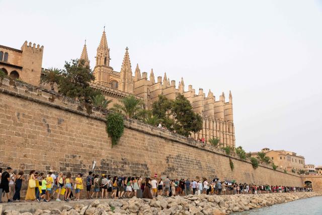 Protesters walk past the Cathedral during a demonstration against overtourism and housing prices in Palma de Mallorca, on the Balearic island of Mallorca, on July 26, 2026. (Photo by JAIME REINA / AFP)