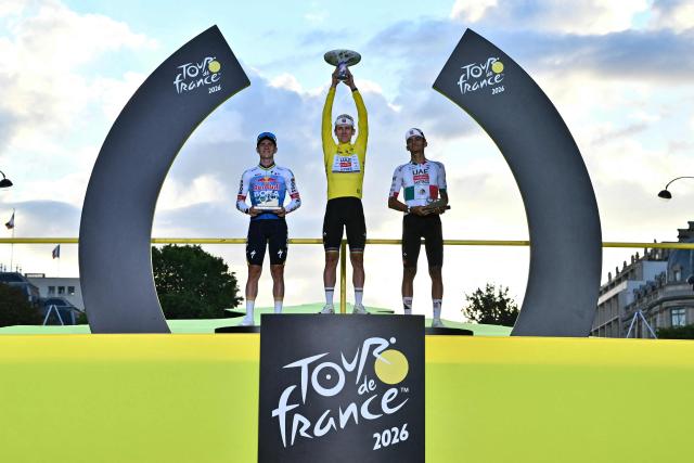 (FILES) Overall winner UAE Team Emirates - XRG's Slovenian rider Tadej Pogacar celebrates on the on the podium with second-placed Red Bull - BORA - hansgrohe team's Belgian rider Remco Evenepoel and third-placed UAE Team Emirates - XRG's Mexican rider Isaac Del Toro after the 21st stage of the 113th edition of the Tour de France cycling race, 88,7 km starting and finishing in Paris, on July 26, 2026. (Photo by Jeff PACHOUD / AFP)