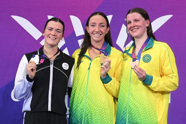 Silver medallist New Zealand's Erika Fairweather (L), gold medallist Australia's Lani Pallister (C) and bronze medallist Australia's Molly Walker celebrate during the medal ceremony for the Women's 1500m Freestyle at the swimming event at the Tollcross International Swimming Centre in Glasgow, on day three of the Commonwealth Games in Glasgow, Scotland, on July 26, 2026. (Photo by Oli SCARFF / AFP)