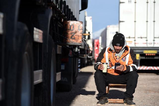 Brazilian truck driver Fernando Roberto waits for the reopening of the highway affected due to several snow storms near the Argentina-Chile border in Uspallata, Medonza province, Argentina on July 26, 2026. Snowfall is forecasted for the next few days on the Andes mountains forcing the clousure of the international road between Argentina and Chile where dozens of trucks are stranded according to local authorities. (Photo by Andres LARROVERE / AFP)