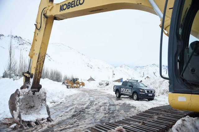 Government workers and police officers clear an affected road due to several snow storms near the Argentina-Chile border, some 183 kms east of the city of Mendoza, Argentina on July 26, 2026. Snowfall is forecasted for the next few days on the Andes mountains forcing the clousure of the international road between Argentina and Chile where dozens of trucks are stranded according to local authorities. (Photo by Andres LARROVERE / AFP)
