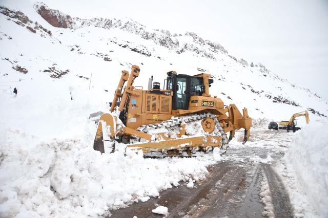 Government workers clear an affected road due to several snow storms near the Argentina-Chile border, some 183 kms east of the city of Mendoza, Argentina on July 26, 2026. Snowfall is forecasted for the next few days on the Andes mountains forcing the clousure of the international road between Argentina and Chile where dozens of trucks are stranded according to local authorities. (Photo by Andres LARROVERE / AFP)