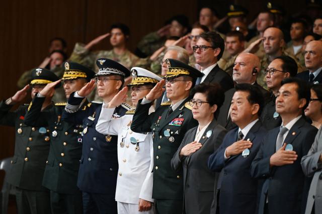 South Korean military officials salute as the national anthem is sung during a national ceremony for the Korean War UN Veterans Day in Seoul on July 27, 2026. (Photo by GREG BAKER / AFP)