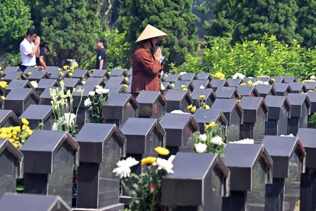 A woman prays at the Ngoc Hoi Martyrs Cemetery in Hanoi on July 27, 2026, on Vietnam's War Invalids and Martyrs' Day. (Photo by Nhac NGUYEN / AFP)