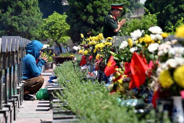 People pray at the graves of fallen soldiers at the Ngoc Hoi Martyrs Cemetery in Hanoi on July 27, 2026, on Vietnam's War Invalids and Martyrs' Day. (Photo by Nhac NGUYEN / AFP)