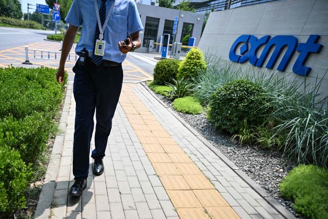 A security personnel walks at an entrance to the ChangXin Memory Technologies (CXMT) factory on the outskirts of Beijing on July 27, 2026. China's leading memory chipmaker soared 470 percent in its market debut in Shanghai on July 27, 2026, briefly surpassing megabank ICBC as the mainland's most valuable company. (Photo by Pedro PARDO / AFP)