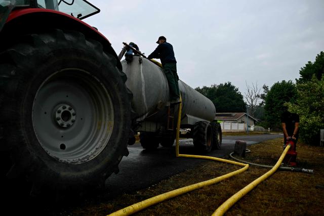 Farmers fill tanks with water to help firefighters battle the fire in Blagon, west of Bordeaux, on July 27, 2026, during wildfires in the Gironde region, southwestern France. Firefighters battled massive blazes tearing through forests across France on July 27, as authorities warned of a fresh heatwave set to engulf the scorched French wine-growing region around the major city of Bordeaux. (Photo by Philippe Lopez / AFP)