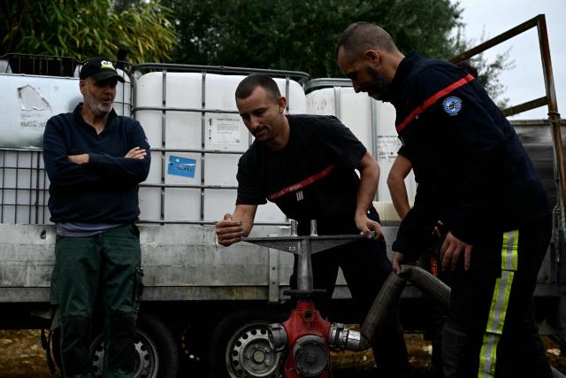 Firefighters fill tanks with water to battle the fire in Blagon, west of Bordeaux, on July 27, 2026, during wildfires in the Gironde region, southwestern France. Firefighters battled massive blazes tearing through forests across France on July 27, as authorities warned of a fresh heatwave set to engulf the scorched French wine-growing region around the major city of Bordeaux. (Photo by Philippe Lopez / AFP)