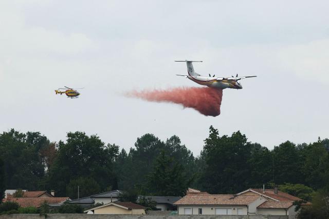 This photograph shows a Bombardier Dash 8 Q400 MR aircraft (R) dropping fire retardant over a forest near Marcheprime, some 30km from Bordeaux, on July 27, 2026, as a wildfire rages through the forest in Gironde, southwestern France. A massive wildfire in France's Gironde department, home to Bordeaux, remained "broadly stable overnight," the local authority said on July 27, 2026. "The situation remained broadly stable overnight, with no major developments. Security and emergency services remain fully mobilised and are continuing their operations on the ground," the local authority said in a statement. (Photo by Alain JOCARD / AFP)