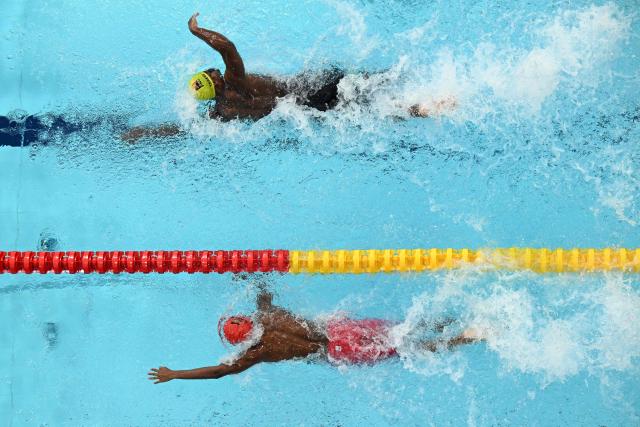 Vanuatu's Leo Lebot (up) and Rwanda's Kean Murenzi Sheja compete in the Men's 100m Freestyle heats at the swimming event at the Tollcross International Swimming Centre in Glasgow, on day four of the Commonwealth Games in Glasgow, Scotland, on July 27, 2026. (Photo by Oli SCARFF / AFP)