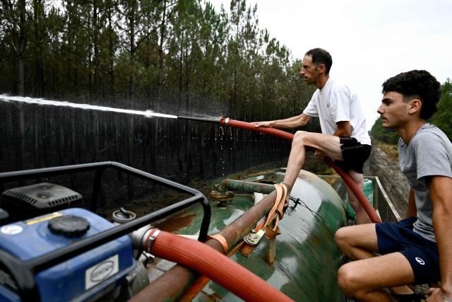Farmers spray water on hotspots to help firefighters battle the wildfire in Saint-Jean-d'Illac, west of Bordeaux, on July 27, 2026, during wildfires in the Gironde region, southwestern France. Firefighters battled massive blazes tearing through forests across France on July 27, as authorities warned of a fresh heatwave set to engulf the scorched French wine-growing region around the major city of Bordeaux. (Photo by Philippe Lopez / AFP)