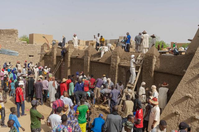 Residents apply mud to a wall during the replastering of the Sankore Mosque, as part of an event marking its 600th anniversary, in Timbuktu, on July 26, 2026. Hundreds gathered in the historic city of Timbuktu to replaster the Sankore Mosque as part of celebrations marking its 600th anniversary. Built in the 14th century, it is one of Timbuktu's three great mosques, alongside Djingareyber and Sidi Yahia. Together, they are unique examples of earthen architecture and played an important role in the early spread of Islam in Africa. The Sankore Mosque, along with the other historic mosques of Timbuktu, was inscribed on UNESCO's World Heritage List in 1988. (Photo by AFP)