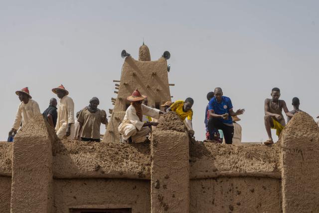 Residents apply mud to a wall during the replastering of the Sankore Mosque, as part of an event marking its 600th anniversary, in Timbuktu, on July 26, 2026. Hundreds gathered in the historic city of Timbuktu to replaster the Sankore Mosque as part of celebrations marking its 600th anniversary. Built in the 14th century, it is one of Timbuktu's three great mosques, alongside Djingareyber and Sidi Yahia. Together, they are unique examples of earthen architecture and played an important role in the early spread of Islam in Africa. The Sankore Mosque, along with the other historic mosques of Timbuktu, was inscribed on UNESCO's World Heritage List in 1988. (Photo by AFP)