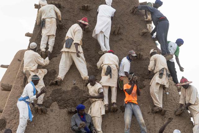 Residents apply mud to the minaret during the replastering of the Sankore Mosque, as part of an event marking its 600th anniversary, in Timbuktu, on July 26, 2026. Hundreds gathered in the historic city of Timbuktu to replaster the Sankore Mosque as part of celebrations marking its 600th anniversary. Built in the 14th century, it is one of Timbuktu's three great mosques, alongside Djingareyber and Sidi Yahia. Together, they are unique examples of earthen architecture and played an important role in the early spread of Islam in Africa. The Sankore Mosque, along with the other historic mosques of Timbuktu, was inscribed on UNESCO's World Heritage List in 1988. (Photo by AFP)