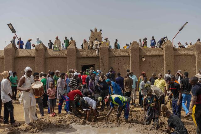 Residents collect mud during the replastering of the Sankore Mosque, as part of an event marking its 600th anniversary, in Timbuktu, on July 26, 2026. Hundreds gathered in the historic city of Timbuktu to replaster the Sankore Mosque as part of celebrations marking its 600th anniversary. Built in the 14th century, it is one of Timbuktu's three great mosques, alongside Djingareyber and Sidi Yahia. Together, they are unique examples of earthen architecture and played an important role in the early spread of Islam in Africa. The Sankore Mosque, along with the other historic mosques of Timbuktu, was inscribed on UNESCO's World Heritage List in 1988. (Photo by AFP)