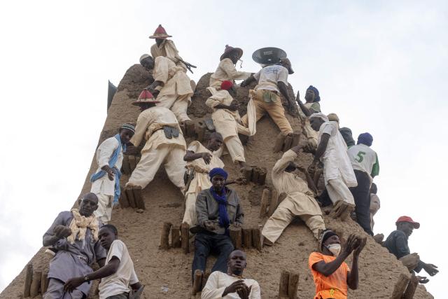Residents apply mud to the minaret during the replastering of the Sankore Mosque, as part of an event marking its 600th anniversary, in Timbuktu, on July 26, 2026. Hundreds gathered in the historic city of Timbuktu to replaster the Sankore Mosque as part of celebrations marking its 600th anniversary. Built in the 14th century, it is one of Timbuktu's three great mosques, alongside Djingareyber and Sidi Yahia. Together, they are unique examples of earthen architecture and played an important role in the early spread of Islam in Africa. The Sankore Mosque, along with the other historic mosques of Timbuktu, was inscribed on UNESCO's World Heritage List in 1988. (Photo by AFP)