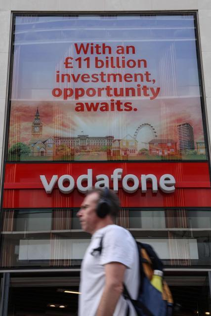 A pedestrian walks past a shop for British telecommunications group Vodafone in central London on July 27, 2026. Vodafone announced on July 27 a nearly 10 percent increase in revenue for the first quarter and raised its forecasts. (Photo by Adrian DENNIS / AFP)