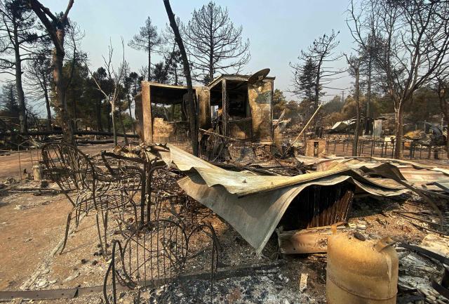 The charred remains of caravans and tents are seen following a wildfire at the Pantano de Burguillo campsite in El Barraco, 100 kilometres west of Madrid, on July 27, 2026. Spain faces two crucial days to bring raging wildfires under control before weather conditions worsen, authorities said on July 27, 2026, though they were making some progress and planned to start returning evacuees to certain areas. The wildfires that broke out in forested areas around the Spanish capital at the height of the summer holidays have forced some 60,000 people to flee their homes, often with just minutes' notice, leaving pets and medicine behind. (Photo by Roland LLOYD PARRY / AFP)