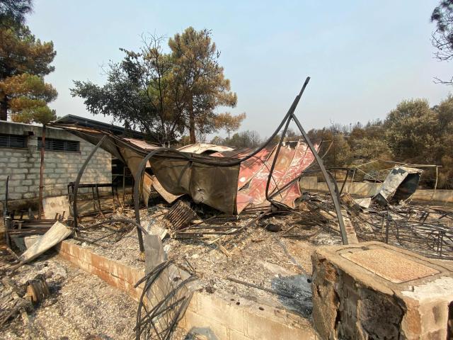 The charred twisted iron frame of a canopy is seen following a wildfire at the Pantano de Burguillo campsite in El Barraco, 100 kilometres west of Madrid, on July 27, 2026. Spain faces two crucial days to bring raging wildfires under control before weather conditions worsen, authorities said on July 27, 2026, though they were making some progress and planned to start returning evacuees to certain areas. The wildfires that broke out in forested areas around the Spanish capital at the height of the summer holidays have forced some 60,000 people to flee their homes, often with just minutes' notice, leaving pets and medicine behind. (Photo by Roland LLOYD PARRY / AFP)