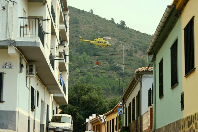 A firefighting helicopter takes off after scooping water in the evacuated town of Chovar, 60 kilometres north of Valencia, to use it against the wildfires ravaging the area. Spain faces two crucial days to bring raging wildfires under control before weather conditions worsen, authorities said on July 27, 2026, though they were making some progress and planned to start returning evacuees to certain areas. The fires in the Iberian country have affected an area of 77,000 hectares (190,000 acres) -- nearly the size of New York City -- according to the authorities. Since the start of the year, fires in Spain have ravaged 150,000 hectares and killed 13 people. (Photo by Jose JORDAN / AFP)