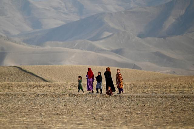 Afghan women and children walk along the foothills on the outskirts of Fayzabad district in Afghanistan's Badakhshan province on July 27, 2026. (Photo by Wakil Kohsar / AFP)