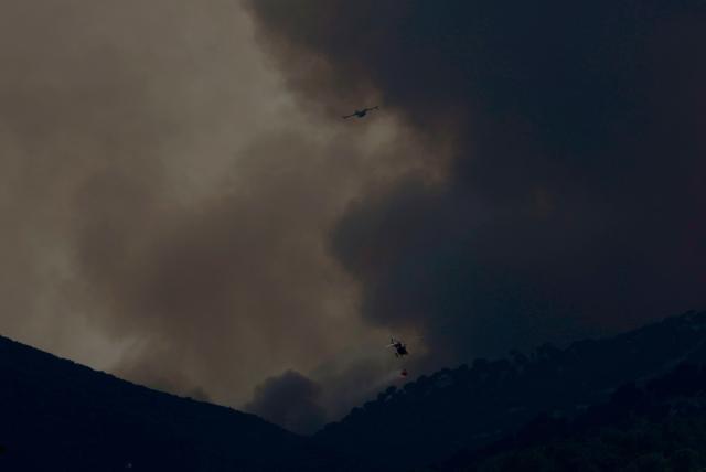 A helicopter and a fixed-wing firefighting aircraft operate above a wildfire near Robledo de Chavela, some 60 kilometres west of Madrid, on July 27, 2026. Spain faces two crucial days to bring raging wildfires under control before weather conditions worsen, authorities said on July 27, 2026, though they were making some progress and planned to start returning evacuees to certain areas. The fires in the Iberian country have affected an area of 77,000 hectares (190,000 acres) -- nearly the size of New York City -- according to the authorities. Since the start of the year, fires in Spain have ravaged 150,000 hectares and killed 13 people. (Photo by Oscar DEL POZO / AFP)