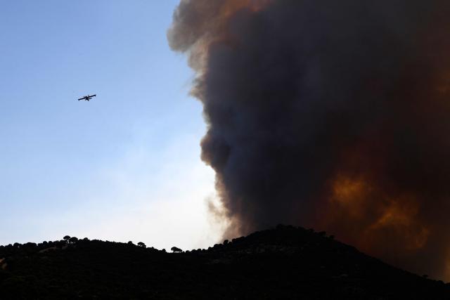 A firefighter airplane overflies a wildfire near the village of Cebreros, Avila province, Spain, on July 27, 2026. Spain faces two crucial days to bring raging wildfires under control before weather conditions worsen, authorities said on July 27, 2026, though they were making some progress and planned to start returning evacuees to certain areas. The fires in the Iberian country have affected an area of 77,000 hectares (190,000 acres) -- nearly the size of New York City -- according to the authorities. Since the start of the year, fires in Spain have ravaged 150,000 hectares and killed 13 people. (Photo by MIGUEL RIOPA / AFP)