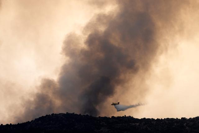 A firefighter airplane drops water on a wildfire near the village of Cebreros, Avila province, Spain, on July 27, 2026. Spain faces two crucial days to bring raging wildfires under control before weather conditions worsen, authorities said on July 27, 2026, though they were making some progress and planned to start returning evacuees to certain areas. The fires in the Iberian country have affected an area of 77,000 hectares (190,000 acres) -- nearly the size of New York City -- according to the authorities. Since the start of the year, fires in Spain have ravaged 150,000 hectares and killed 13 people. (Photo by MIGUEL RIOPA / AFP)
