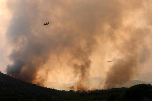 Firefighter airplanes drop water on a wildfire near the village of Cebreros, Avila province, Spain, on July 27, 2026. Spain faces two crucial days to bring raging wildfires under control before weather conditions worsen, authorities said on July 27, 2026, though they were making some progress and planned to start returning evacuees to certain areas. The fires in the Iberian country have affected an area of 77,000 hectares (190,000 acres) -- nearly the size of New York City -- according to the authorities. Since the start of the year, fires in Spain have ravaged 150,000 hectares and killed 13 people. (Photo by MIGUEL RIOPA / AFP)