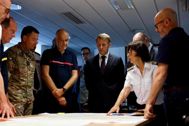 France's President Emmanuel Macron (C) and SDIS 33 Fire and Rescue Service Departemental director Marc Vermeulen (3L) listen to Prefect of Gironde region Sophie Brocas (2R) during a situation briefing in the crisis room at the Departmental Fire and Rescue Operational Center (CODIS) in Bordeaux, following wildfires in the area, southwestern France, on July 27, 2026. France has been battered by three heatwaves since May as part of increasingly common extreme weather episodes linked to climate change, causing excess deaths, drying up rivers and fuelling wildfires. Scientists have long warned that climate change caused by human use of fossil fuels will make periods of drought more intense and longer-lasting, creating the ideal conditions for wildfires. (Photo by Kenzo TRIBOUILLARD / POOL / AFP)