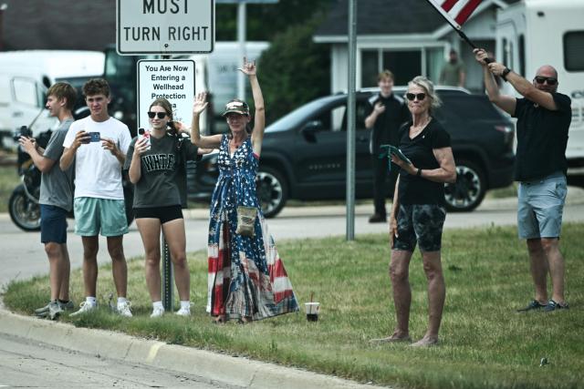 People line the road as the motorcade of US President Donald Trump travels from the Oakland County International Airport to General Motors' Milford Proving Ground in Milford, Michigan, on July 27, 2026. (Photo by Brendan SMIALOWSKI / AFP)