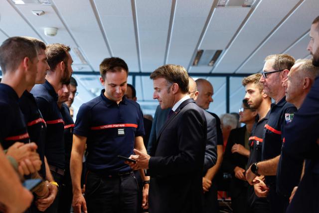 France's President Emmanuel Macron (C) speaks with personnel engaged in firefighting efforts during a visit to the Departmental Fire and Rescue Operational Center (CODIS) in Bordeaux, following wildfires in the area, southwestern France, on July 27, 2026. France has been battered by three heatwaves since May as part of increasingly common extreme weather episodes linked to climate change, causing excess deaths, drying up rivers and fuelling wildfires. Scientists have long warned that climate change caused by human use of fossil fuels will make periods of drought more intense and longer-lasting, creating the ideal conditions for wildfires. (Photo by Kenzo TRIBOUILLARD / POOL / AFP)
