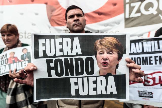 A social movement activist holds a placard reading "Out, Fund, Out" during a protest against the visit of International Monetary Fund (IMF) Managing Director Kristalina Georgieva at Plaza de Mayo in Buenos Aires on July 27, 2026. (Photo by Nicolas SUAREZ / AFP)