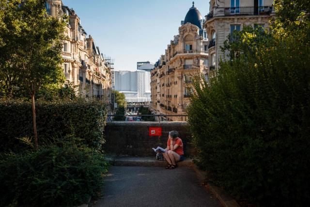 A woman reads a book in a park in Paris on July 27, 2026. (Photo by DIMITAR DILKOFF / AFP)