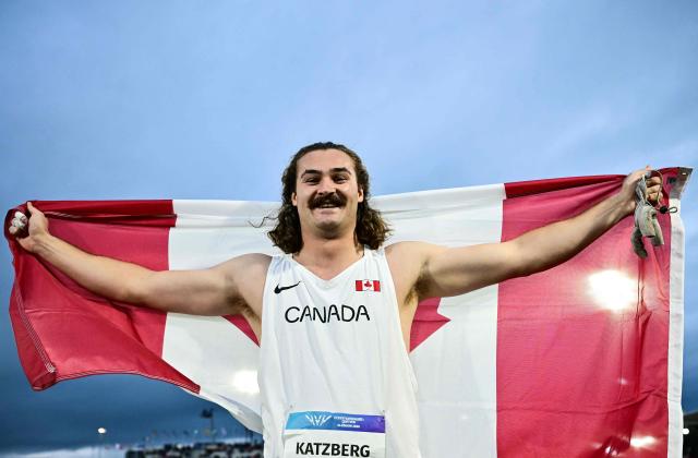 Winner Canada's Ethan Katzberg celebrates with Canada's flag after competing in the men's hammer throw final during the athletics event at the Scotstoun Stadium in Glasgow, on day four of the Commonwealth Games in Glasgow, Scotland, on July 27, 2026. (Photo by Ben STANSALL / AFP)