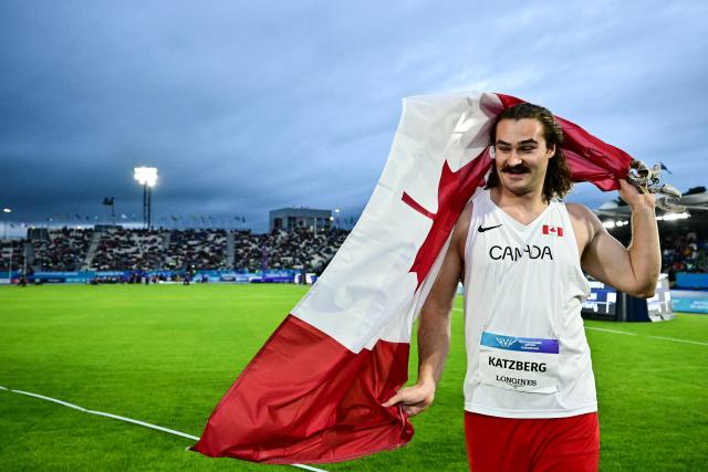 Winner Canada's Ethan Katzberg celebrates with Canada's flag after competing in the men's hammer throw final during the athletics event at the Scotstoun Stadium in Glasgow, on day four of the Commonwealth Games in Glasgow, Scotland, on July 27, 2026. (Photo by Ben STANSALL / AFP)