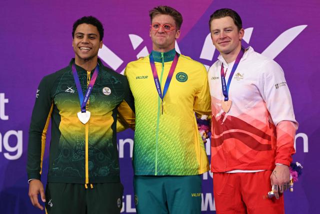Silver medallist South Africa's Michael Houlie (L), gold medallist Australia's Sam Williamson (C) and bronze medallist England's Adam Ramsay-Peaty celebrate during the Men's 50m Breaststroke Medal Ceremony at the swimming event at the Tollcross International Swimming Centre in Glasgow, on day four of the Commonwealth Games in Glasgow, Scotland, on July 27, 2026. (Photo by Oli SCARFF / AFP)