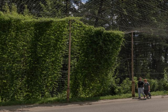Pedestrians walk along a road covered with anti-drone nets, in the town of Izium, in the eastern Kharkiv region on July 27, 2026, amid the Russian invasion of Ukraine. (Photo by Roman PILIPEY / AFP)