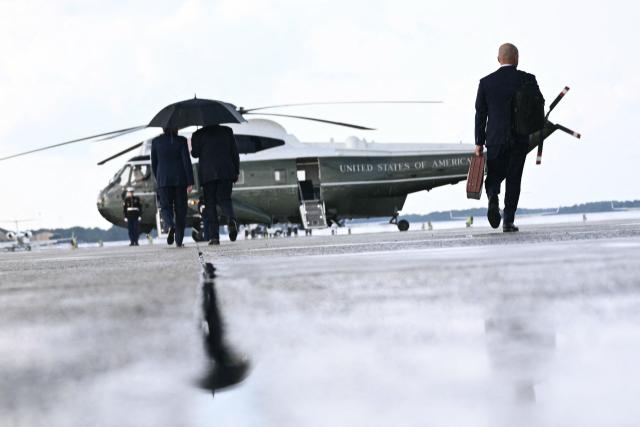 US President Donald Trump walks under an umbrella to board Marine One at Joint Base Andrews, Maryland, on July 27, 2026. Trump is returning from Milford, Michigan, where he delivered remarks at General Motors’ vehicle testing site Milford Proving Ground. (Photo by Brendan SMIALOWSKI / AFP)