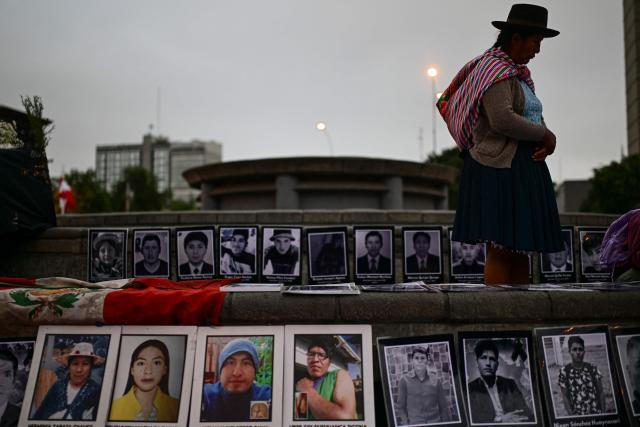A person stands next to photographs of victims during a vigil by relatives of victims of crimes allegedly committed by the Peruvian state outside the Palace of Justice in Lima on July 27, 2026. (Photo by Ernesto BENAVIDES / AFP)