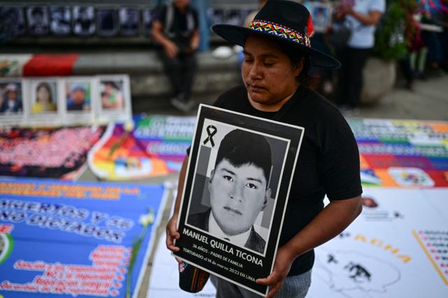 A person holds a portrait of a victim during a vigil by relatives of victims of crimes allegedly committed by the Peruvian state outside the Palace of Justice in Lima on July 27, 2026. (Photo by Ernesto BENAVIDES / AFP)