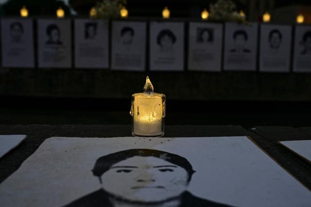 Photographs of victims and candles are displayed during a vigil by relatives of victims of crimes allegedly committed by the Peruvian state outside the Palace of Justice in Lima on July 27, 2026. (Photo by Ernesto BENAVIDES / AFP)