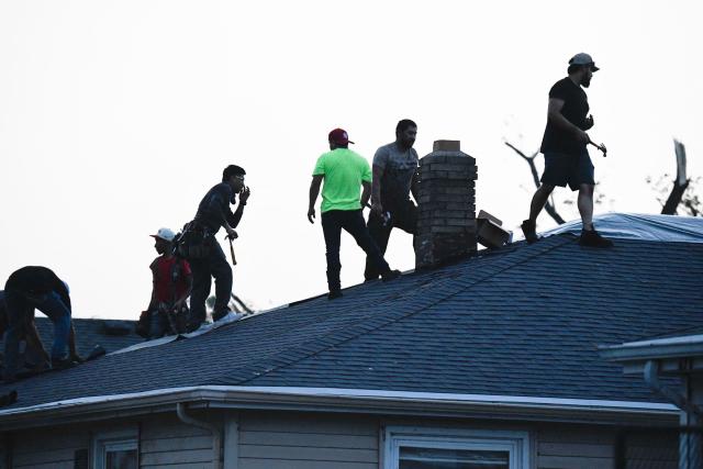 People repair a damaged roof after a tornado ripped through parts of Wisconsin in Menasha, Wisconsin, on July 27, 2026. (Photo by OCTAVIO JONES / AFP)