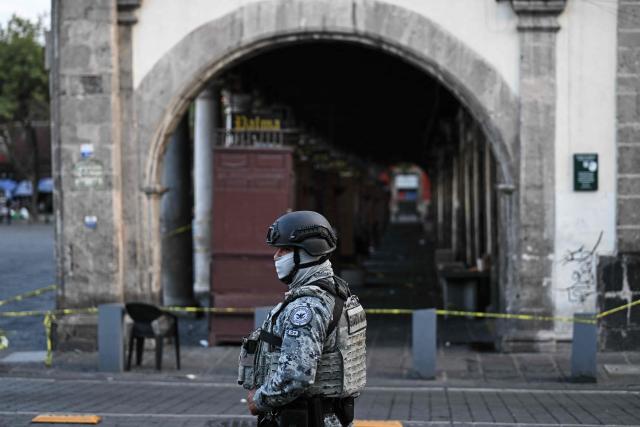 A National Guard member stands guard at the crime scene where one man was killed and two others were wounded in an armed attack at Plaza de Santo Domingo in Mexico City's historic center on July 27, 2026. A broad-daylight shooting in Mexico City left one person dead and two others injured just a few blocks from Mexico City's central Zocalo square and the presidential palace, where President Claudia Sheinbaum works and resides. (Photo by Yuri CORTEZ / AFP)