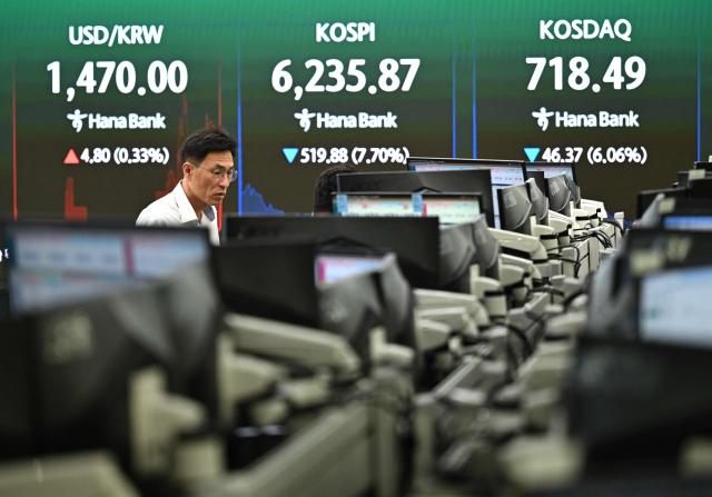 A currency dealer watches monitors as an electronic screen shows South Korea's benchmark stock index (KOSPI) in a foreign exchange dealing room at the Hana Bank headquarters in Seoul on July 28, 2026. Japanese and Korean shares dived in early trade on July 28, after US semiconductor chip stocks fell following a report of a breakthrough that could boost China's computer chip industry. (Photo by Jung Yeon-je / AFP)