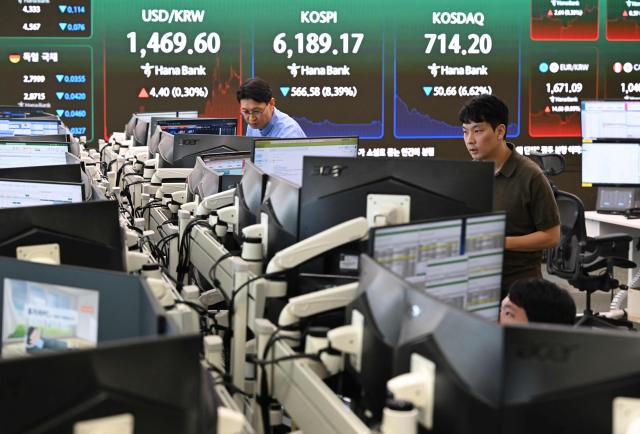 Currency dealers watch monitors as an electronic screen shows South Korea's benchmark stock index (KOSPI) in a foreign exchange dealing room at the Hana Bank headquarters in Seoul on July 28, 2026. Japanese and Korean shares dived in early trade on July 28, after US semiconductor chip stocks fell following a report of a breakthrough that could boost China's computer chip industry. (Photo by Jung Yeon-je / AFP)