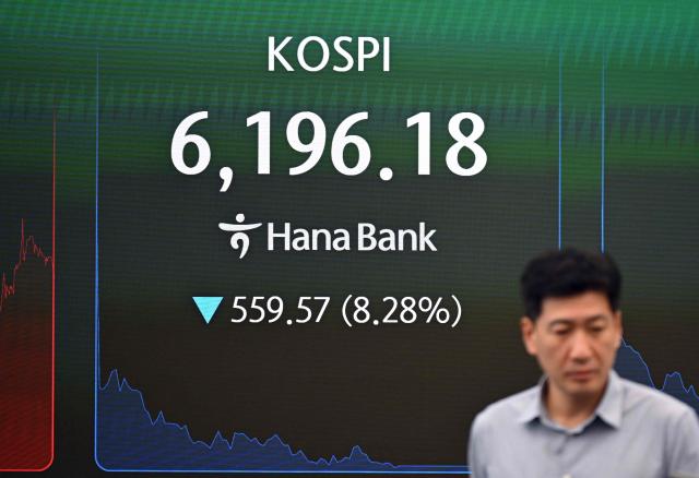 A currency dealer walks past an electronic screen showing South Korea's benchmark stock index (KOSPI) in a foreign exchange dealing room at the Hana Bank headquarters in Seoul on July 28, 2026. Japanese and Korean shares dived in early trade on July 28, after US semiconductor chip stocks fell following a report of a breakthrough that could boost China's computer chip industry. (Photo by Jung Yeon-je / AFP)