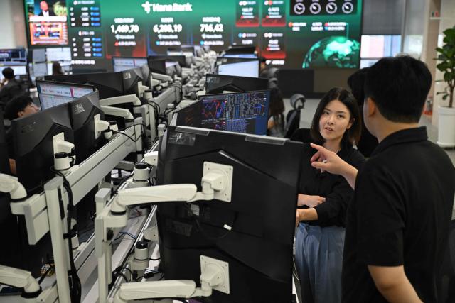 Currency dealers watch monitors as an electronic screen shows South Korea's benchmark stock index (KOSPI) in a foreign exchange dealing room at the Hana Bank headquarters in Seoul on July 28, 2026. Japanese and Korean shares dived in early trade on July 28, after US semiconductor chip stocks fell following a report of a breakthrough that could boost China's computer chip industry. (Photo by Jung Yeon-je / AFP)
