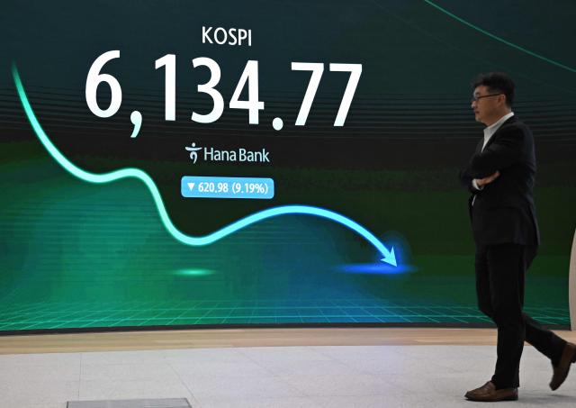 A man walks past an electronic screen showing South Korea's benchmark stock index (KOSPI) in a foreign exchange dealing room at the Hana Bank headquarters in Seoul on July 28, 2026. Japanese and Korean shares dived in early trade on July 28, after US semiconductor chip stocks fell following a report of a breakthrough that could boost China's computer chip industry. (Photo by Jung Yeon-je / AFP)